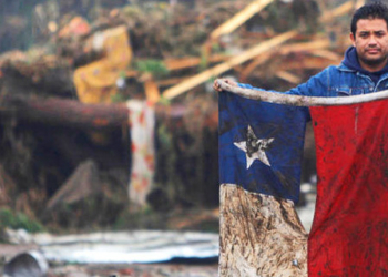 A man holds up a Chilean flag in a flooded area after an earthquake in Pelluhue, some 322 kms, about 200 miles, southwest of Santiago, Sunday, Feb. 28, 2010. A 8.8-magnitude earthquake hit Chile early Saturday. (AP Photo/Roberto Candia)
