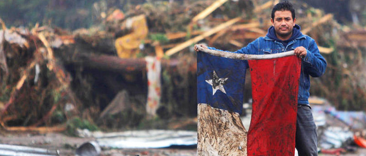 A man holds up a Chilean flag in a flooded area after an earthquake in Pelluhue, some 322 kms, about 200 miles, southwest of Santiago, Sunday, Feb. 28, 2010. A 8.8-magnitude earthquake hit Chile early Saturday. (AP Photo/Roberto Candia)
